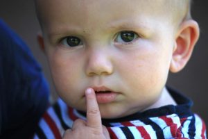 Babygesicht, süßes Baby mit Finger am Mund